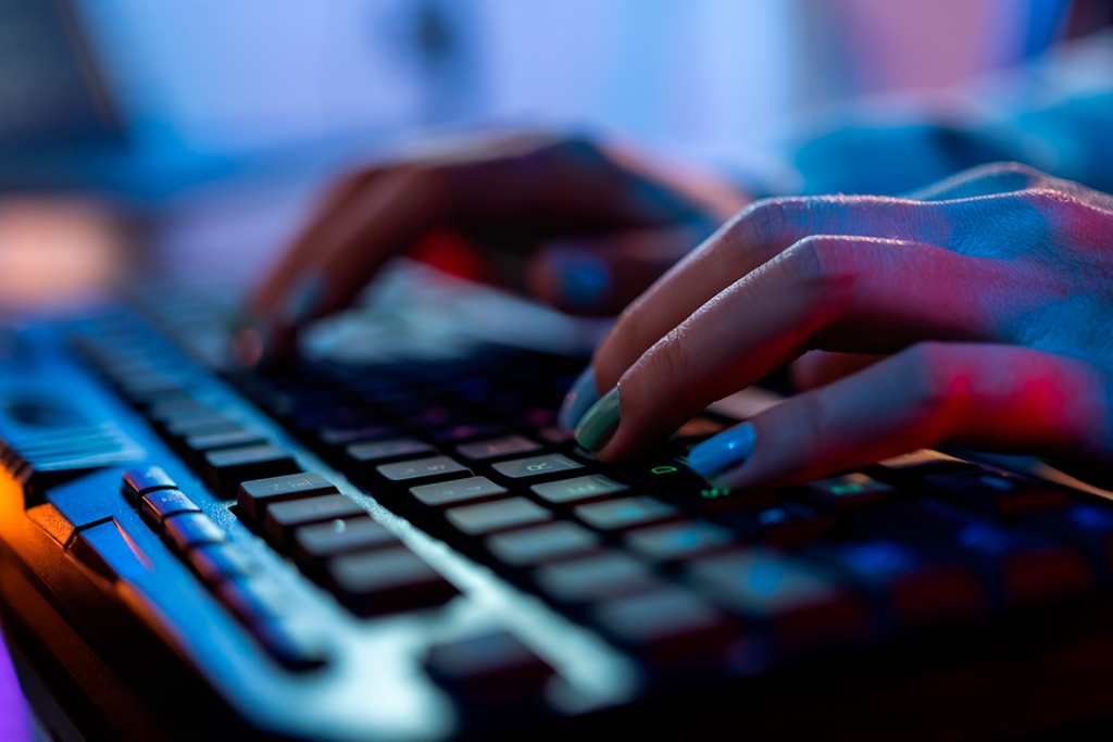 Mãos femininas com unhas coloridas digitam em teclado