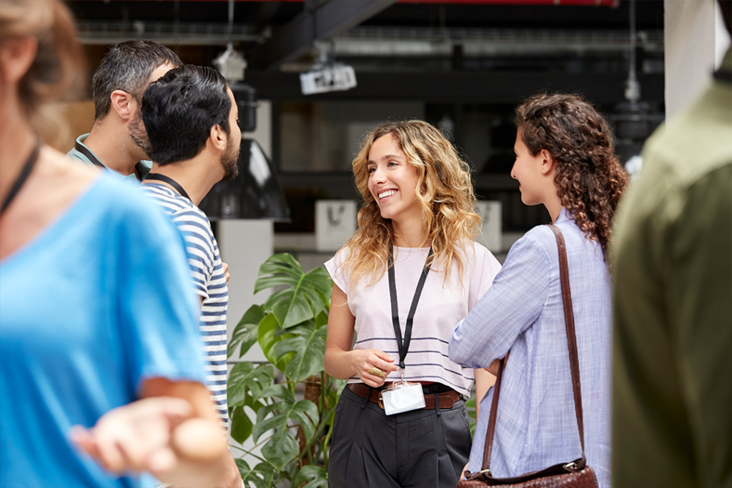 Grupo de profissionais interage em um evento de networking, demonstrando como a comunicação interpessoal fortalece conexões no ambiente de trabalho