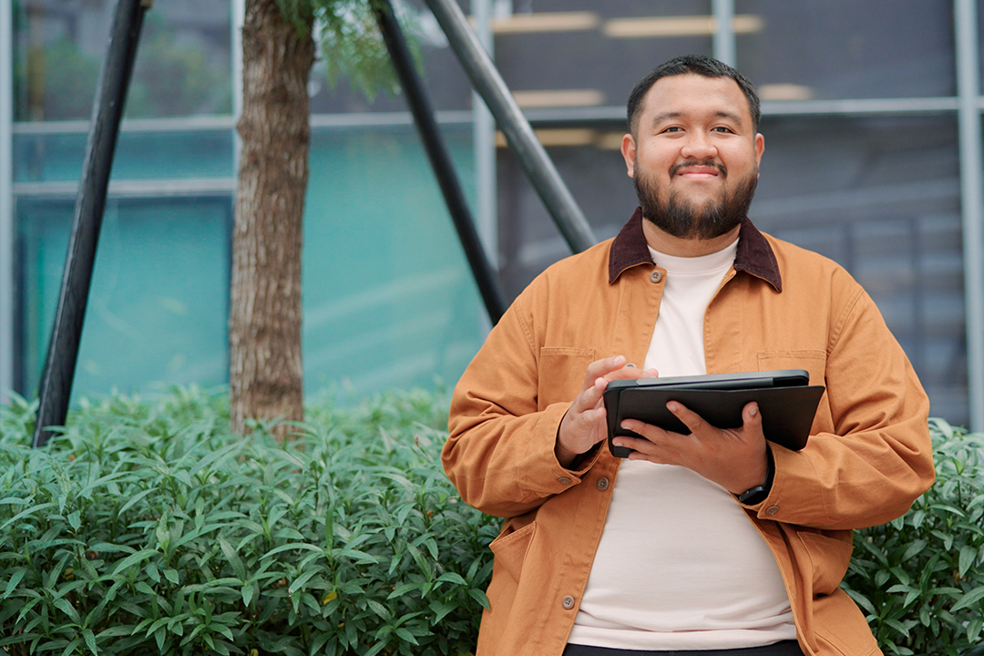 Homem sorridente com um tablet na mão após montar uma apresentação com base nos elementos da narrativa