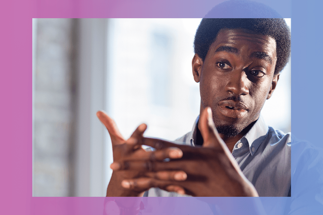 Homem negro entrelaçando os dedos das mãos e usando a linguagem verbal em uma apresentação