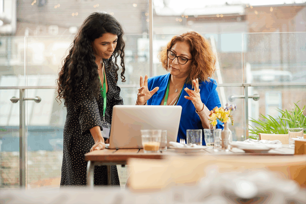 Duas mulheres olhando para um notebook e analisando métricas para avaliar o sucesso de um evento