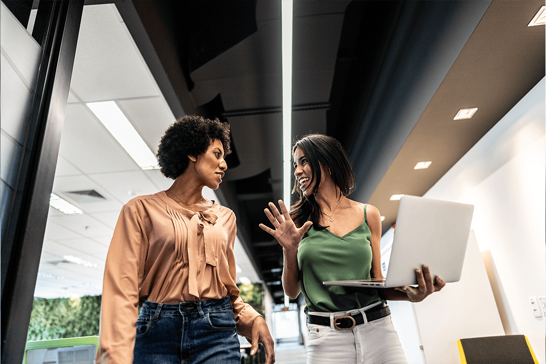 Duas mulheres, em ambiente corporativa, exercitando a comunicação assertiva